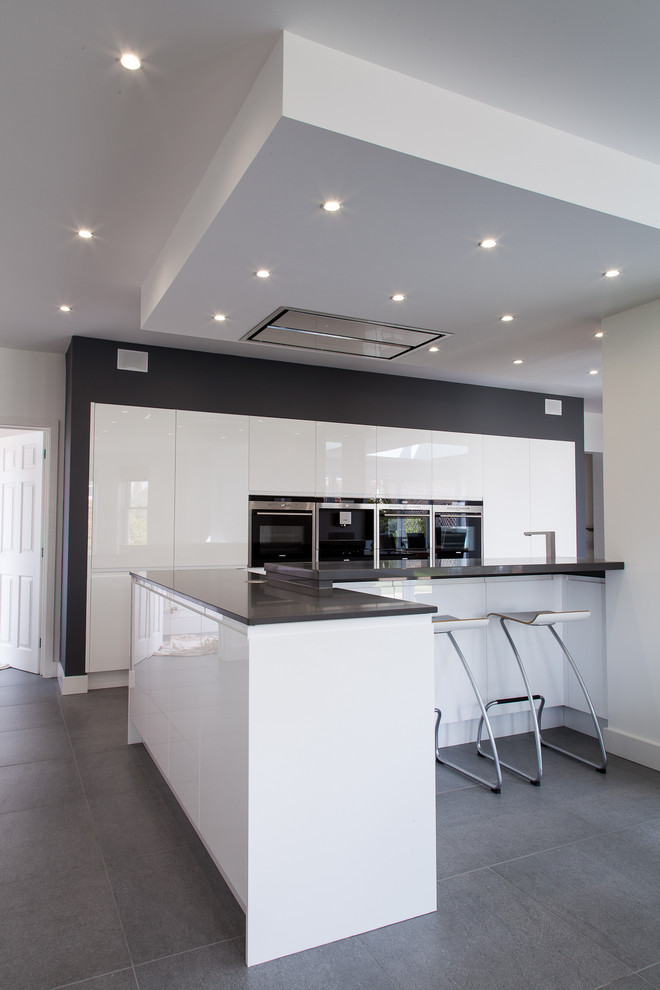 Mittelgroße Moderne Wohnküche mit flächenbündigen Schrankfronten, Quarzwerkstein-Arbeitsplatte, Küchengeräten aus Edelstahl und Kücheninsel in Hertfordshire