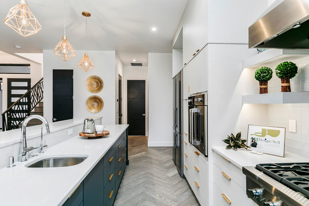 Large contemporary u-shaped kitchen/diner in Boise with a submerged sink, flat-panel cabinets, white cabinets, engineered stone countertops, grey splashback, glass tiled splashback, stainless steel appliances, light hardwood flooring, an island, beige floors and white worktops.