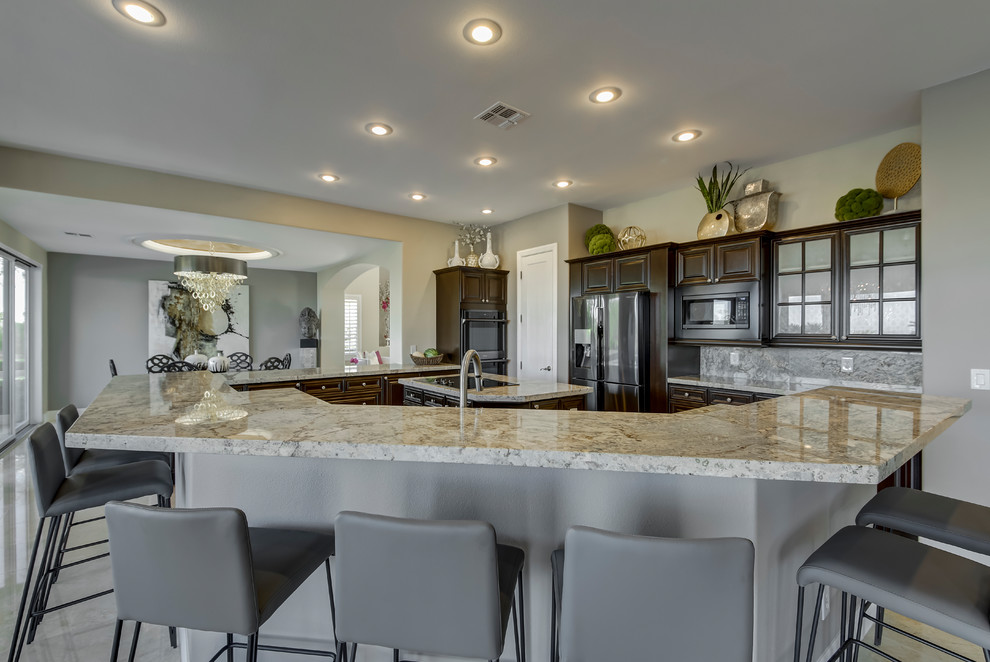 Large transitional u-shaped marble floor and beige floor eat-in kitchen photo in Las Vegas with a double-bowl sink, raised-panel cabinets, dark wood cabinets, granite countertops, gray backsplash, stone slab backsplash, stainless steel appliances, an island and brown countertops
