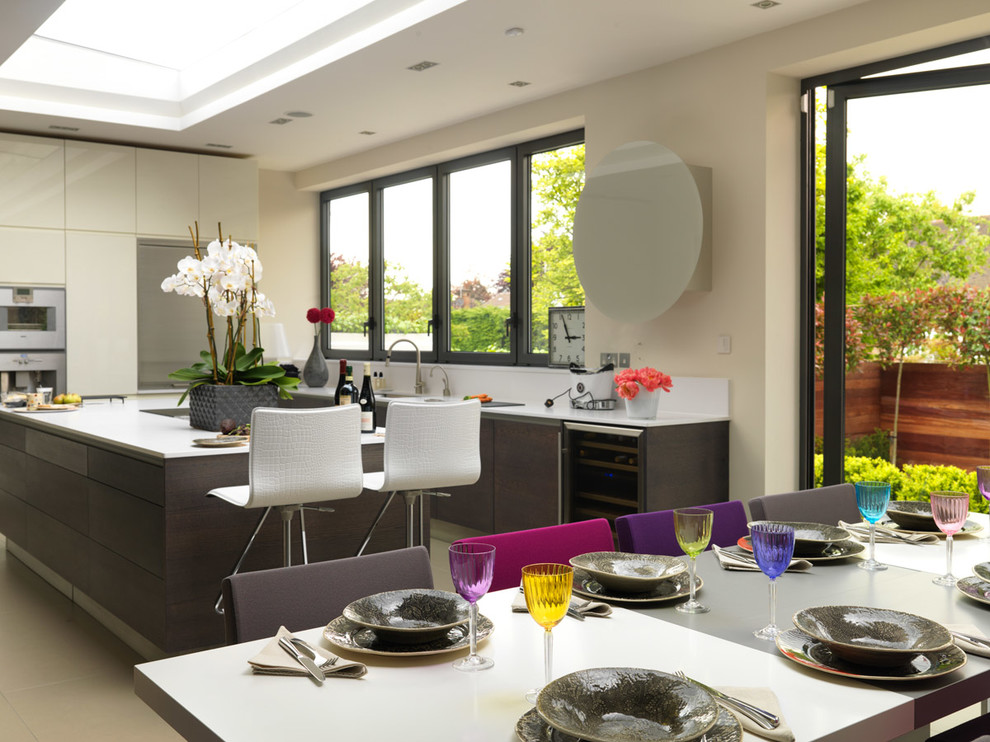 This is an example of a large contemporary l-shaped kitchen/diner in London with an integrated sink, flat-panel cabinets, dark wood cabinets, quartz worktops, white splashback, glass sheet splashback, stainless steel appliances, ceramic flooring and an island.