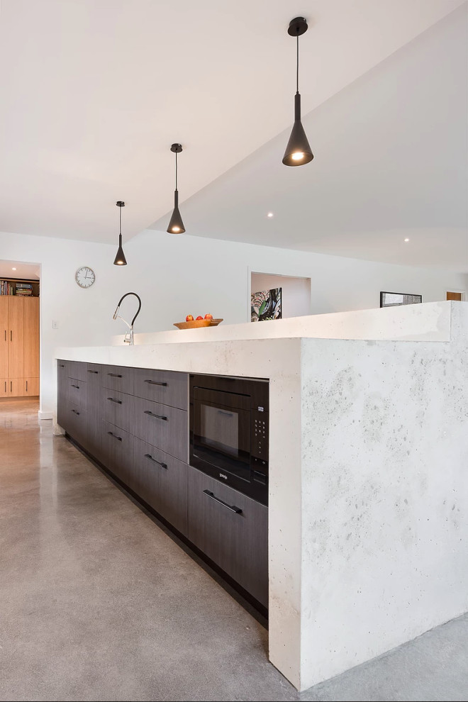 Photo of a large contemporary galley open plan kitchen in Perth with medium wood cabinets, concrete worktops, black splashback, window splashback, stainless steel appliances, concrete flooring, an island, grey floors and white worktops.
