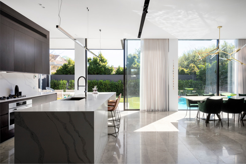 На фото: параллельная кухня-гостиная в современном стиле с врезной мойкой, плоскими фасадами, серыми фасадами, островом, серым полом и серой столешницей с