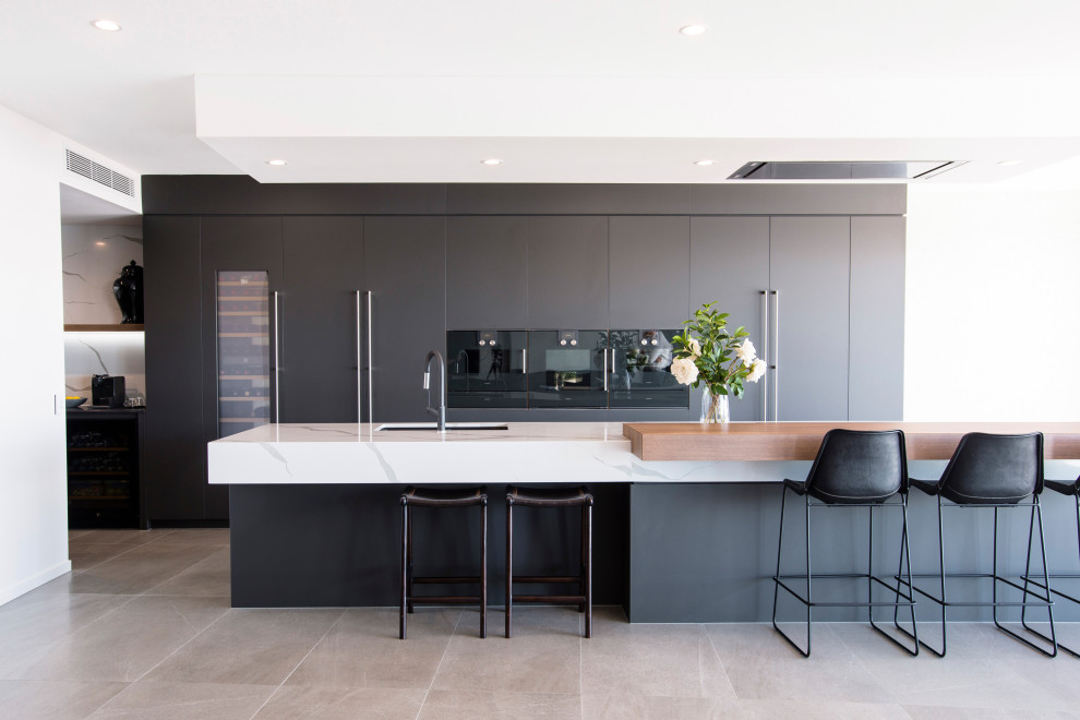 Zweizeilige Moderne Küche mit Unterbauwaschbecken, flächenbündigen Schrankfronten, grauen Schränken, schwarzen Elektrogeräten, Kücheninsel, grauem Boden und weißer Arbeitsplatte in Brisbane