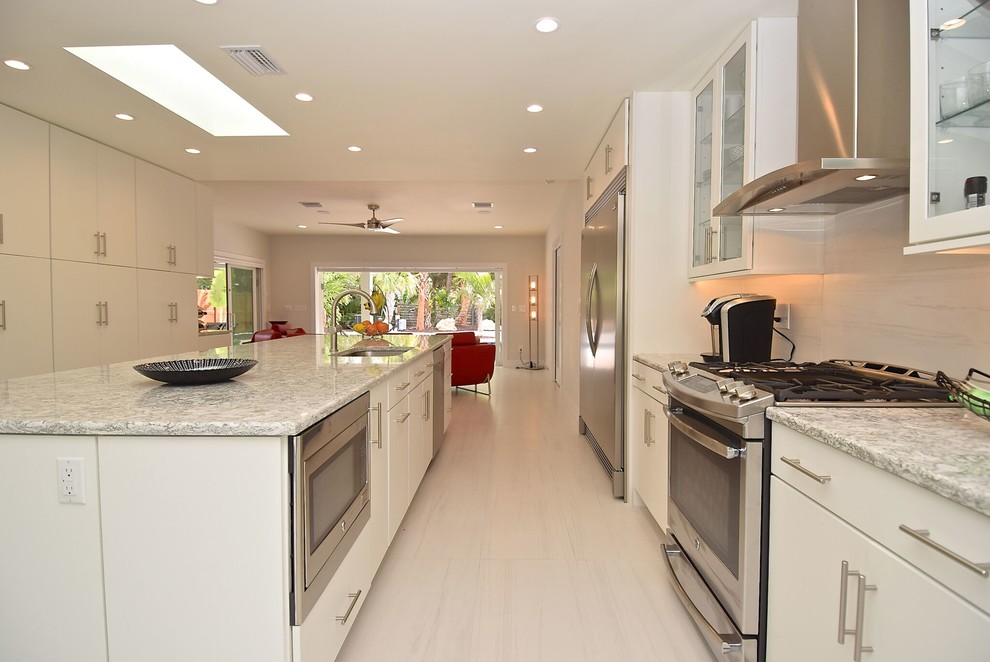 Photo of a large contemporary single-wall kitchen/diner in Tampa with a submerged sink, glass-front cabinets, white cabinets, granite worktops, stainless steel appliances, laminate floors, an island and white floors.