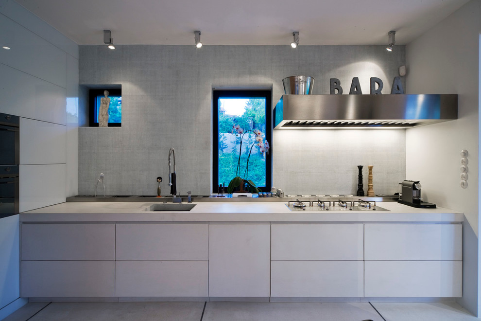Moderne Küche mit Waschbecken, flächenbündigen Schrankfronten, weißen Schränken und Küchengeräten aus Edelstahl in Sonstige