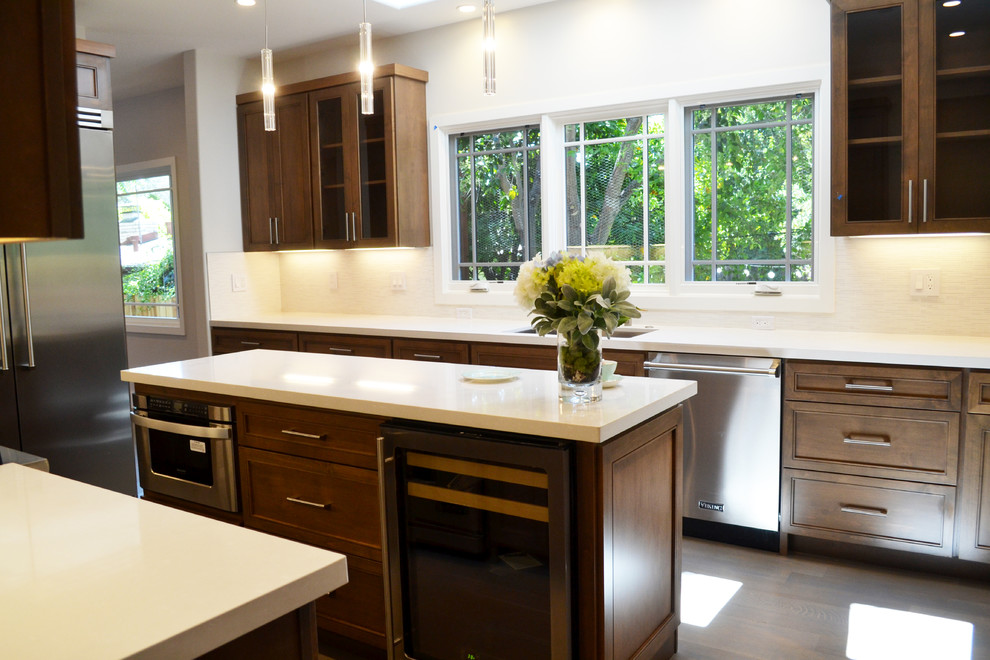 Inspiration for a mid-sized transitional light wood floor kitchen remodel in San Francisco with shaker cabinets, medium tone wood cabinets, quartz countertops, white backsplash, porcelain backsplash, stainless steel appliances and an island