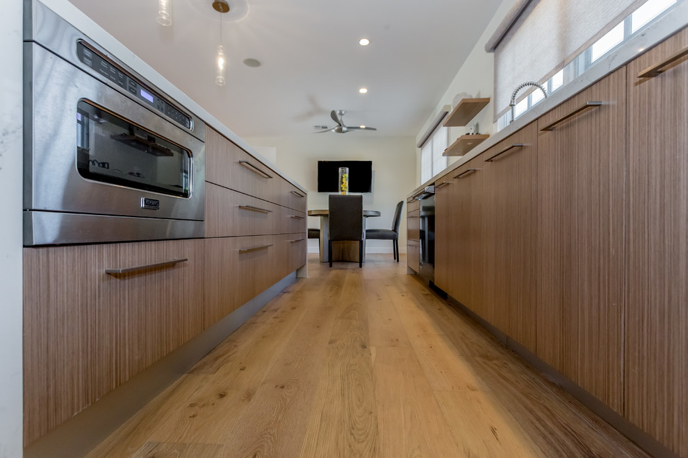 Idéer för stora funkis kök, med en undermonterad diskho, släta luckor, skåp i mellenmörkt trä, marmorbänkskiva, rostfria vitvaror, ljust trägolv, en köksö och beiget golv