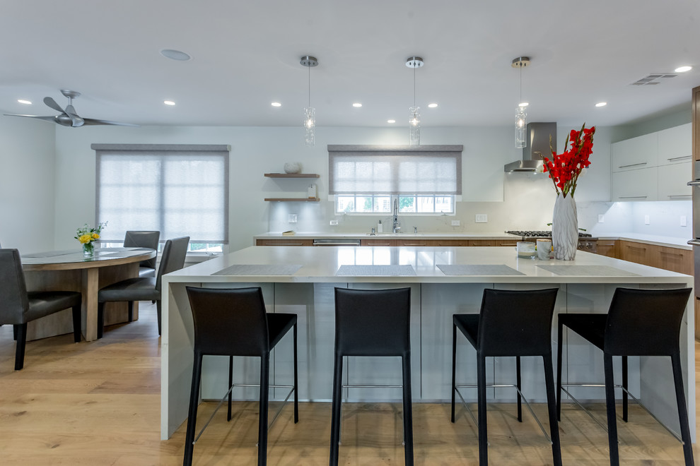 This is an example of a large contemporary u-shaped open plan kitchen in San Francisco with a submerged sink, flat-panel cabinets, medium wood cabinets, marble worktops, stainless steel appliances, light hardwood flooring, an island and beige floors.