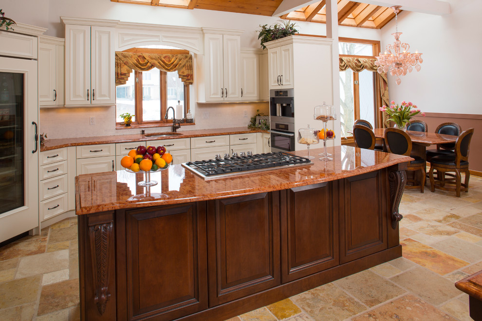 Foto på ett stort vintage orange kök och matrum, med en undermonterad diskho, luckor med upphöjd panel, vitt stänkskydd, stänkskydd i stenkakel, integrerade vitvaror, travertin golv, flera köksöar, vita skåp och granitbänkskiva