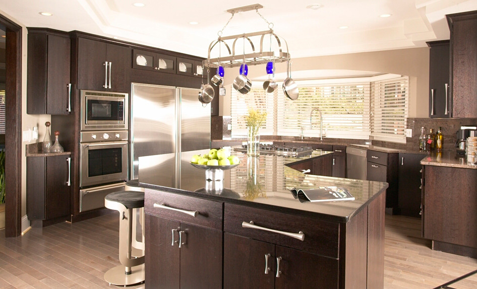 Example of a trendy kitchen design in St Louis with an undermount sink, dark wood cabinets, stainless steel appliances and an island