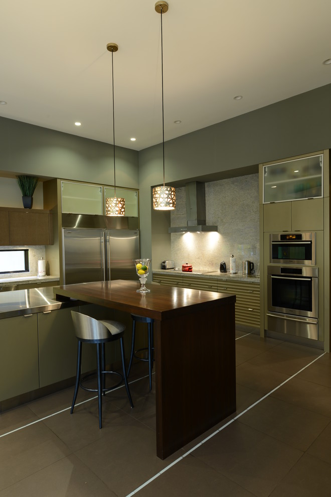 Inspiration for a large contemporary l-shaped kitchen/diner in Indianapolis with a double-bowl sink, glass-front cabinets, green cabinets, stainless steel worktops, grey splashback, stainless steel appliances, ceramic flooring and a breakfast bar.