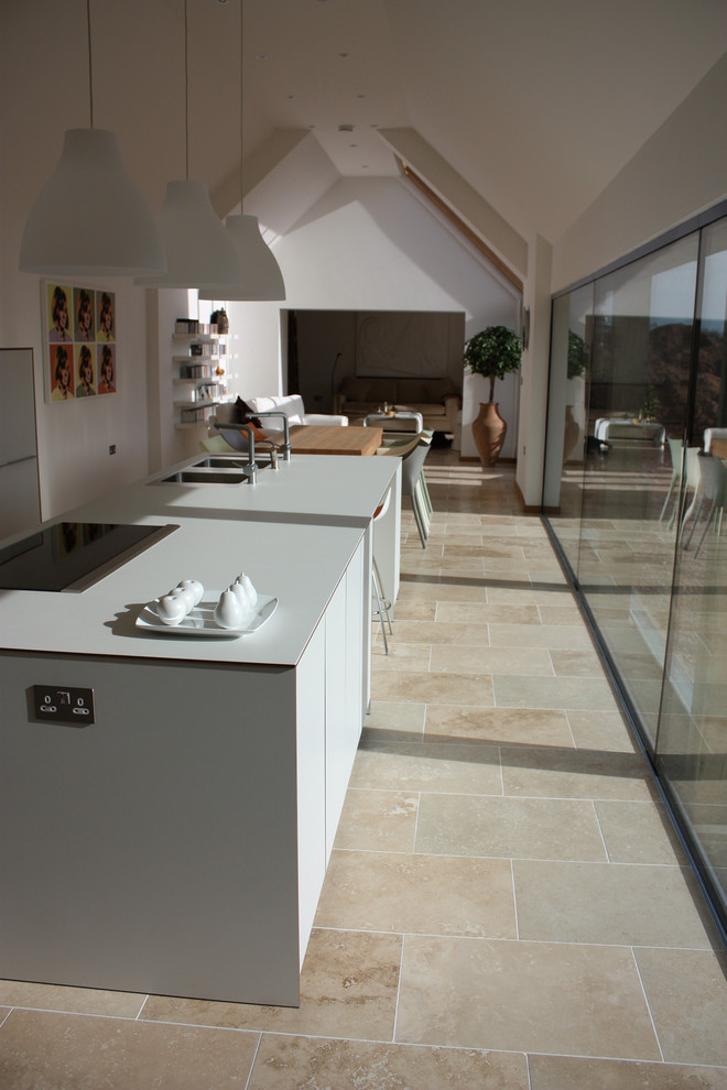 Design ideas for a medium sized contemporary galley kitchen/diner in Gloucestershire with a built-in sink, flat-panel cabinets, white cabinets, marble worktops, stainless steel appliances, travertine flooring and an island.