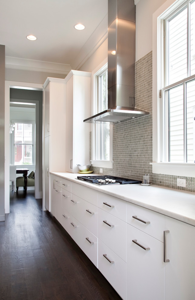 Exempel på ett modernt kök, med släta luckor, vita skåp, marmorbänkskiva, grått stänkskydd, rostfria vitvaror och mörkt trägolv