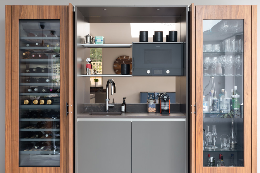 Exempel på ett stort modernt grå grått kök med öppen planlösning, med en integrerad diskho, luckor med glaspanel, grå skåp, bänkskiva i kvartsit, stänkskydd med metallisk yta, spegel som stänkskydd, svarta vitvaror och en köksö