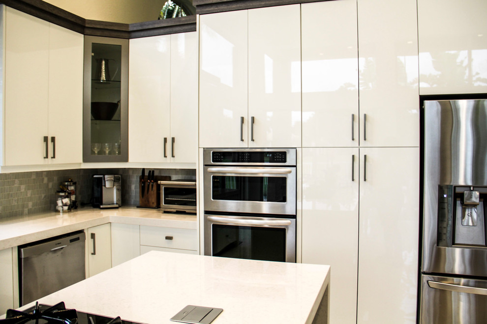 Foto på ett mellanstort funkis kök, med luckor med glaspanel, vita skåp, grått stänkskydd, en undermonterad diskho, bänkskiva i kvarts, stänkskydd i glaskakel, rostfria vitvaror, marmorgolv, en köksö och beiget golv