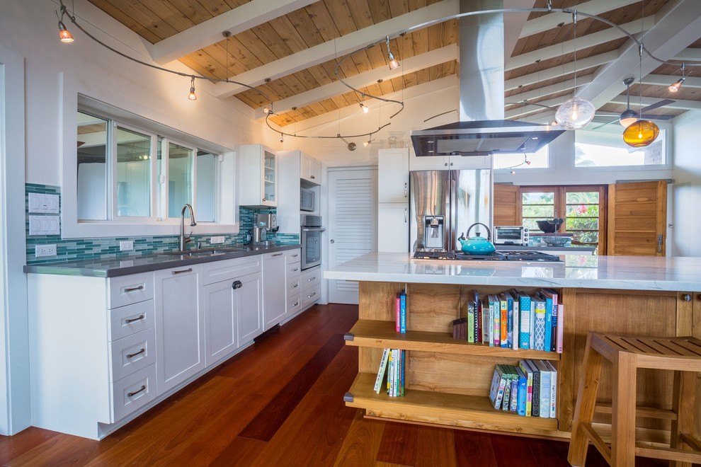 Example of a large beach style u-shaped medium tone wood floor open concept kitchen design in Hawaii with a double-bowl sink, shaker cabinets, white cabinets, quartz countertops, green backsplash, glass tile backsplash, stainless steel appliances and an island
