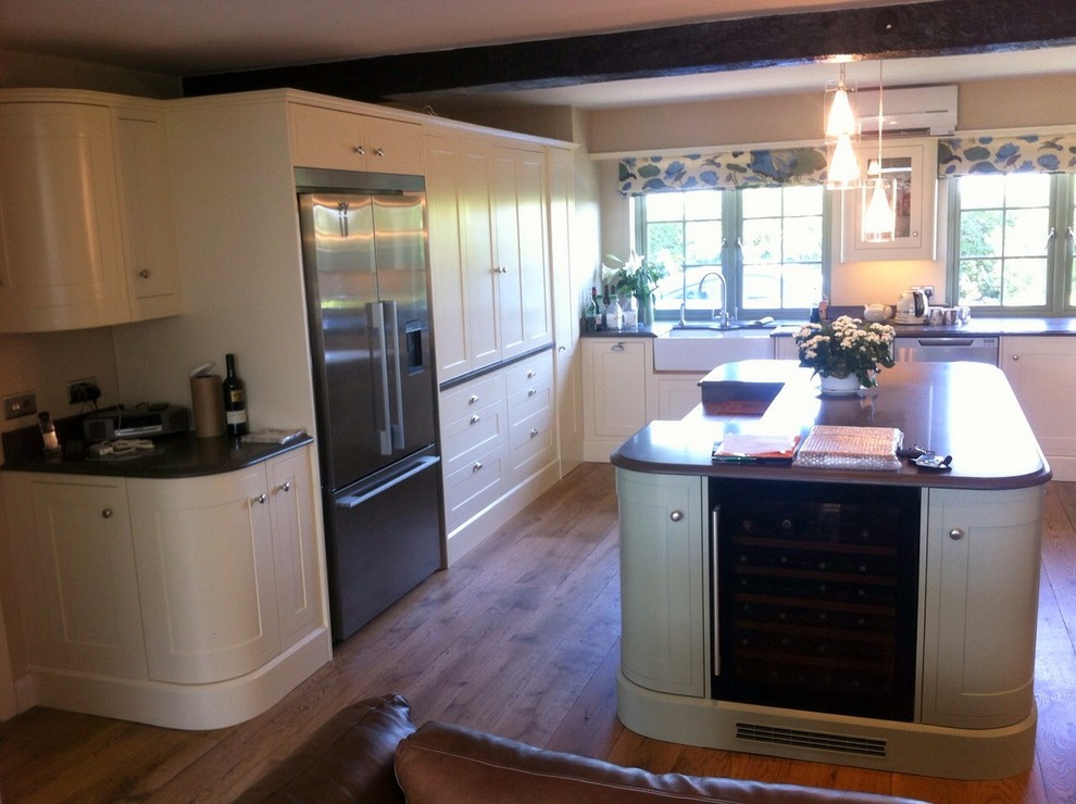 Foto de cocinas en U clásico con fregadero de doble seno, salpicadero verde, suelo de madera en tonos medios y península