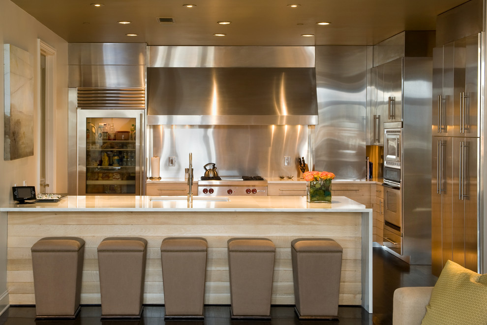 Immagine di un cucina con isola centrale minimal con lavello sottopiano, ante lisce, ante in acciaio inossidabile, paraspruzzi a effetto metallico, elettrodomestici in acciaio inossidabile e parquet scuro
