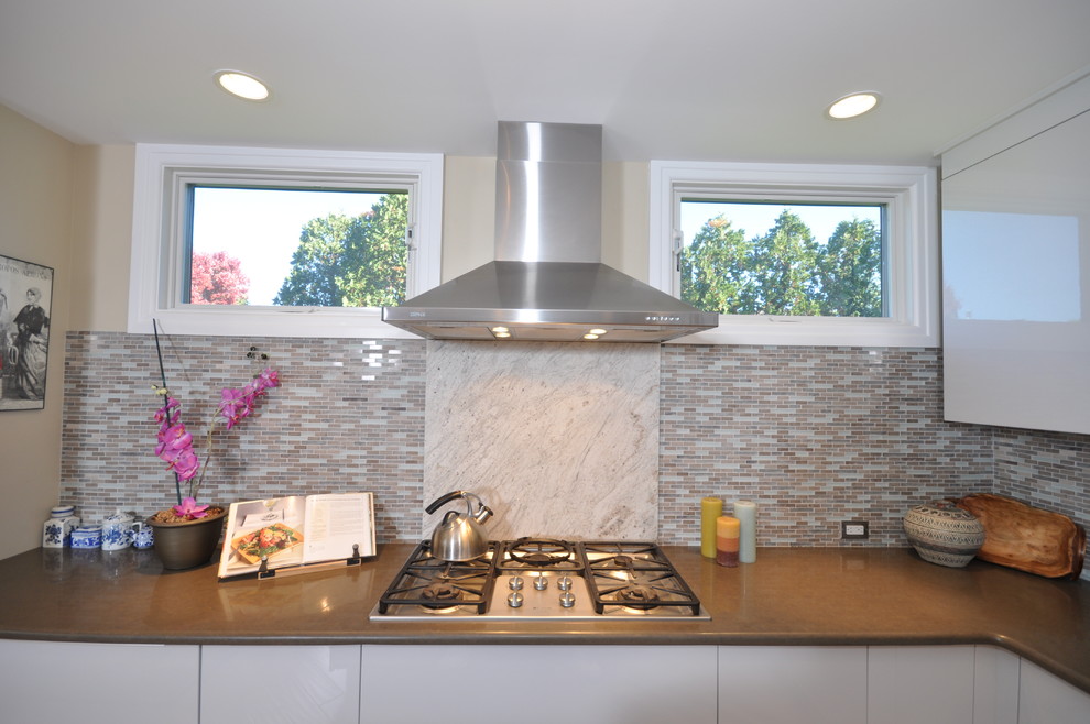 Inspiration for a large contemporary l-shaped light wood floor eat-in kitchen remodel in Philadelphia with an undermount sink, flat-panel cabinets, white cabinets, granite countertops, gray backsplash, mosaic tile backsplash, stainless steel appliances and an island