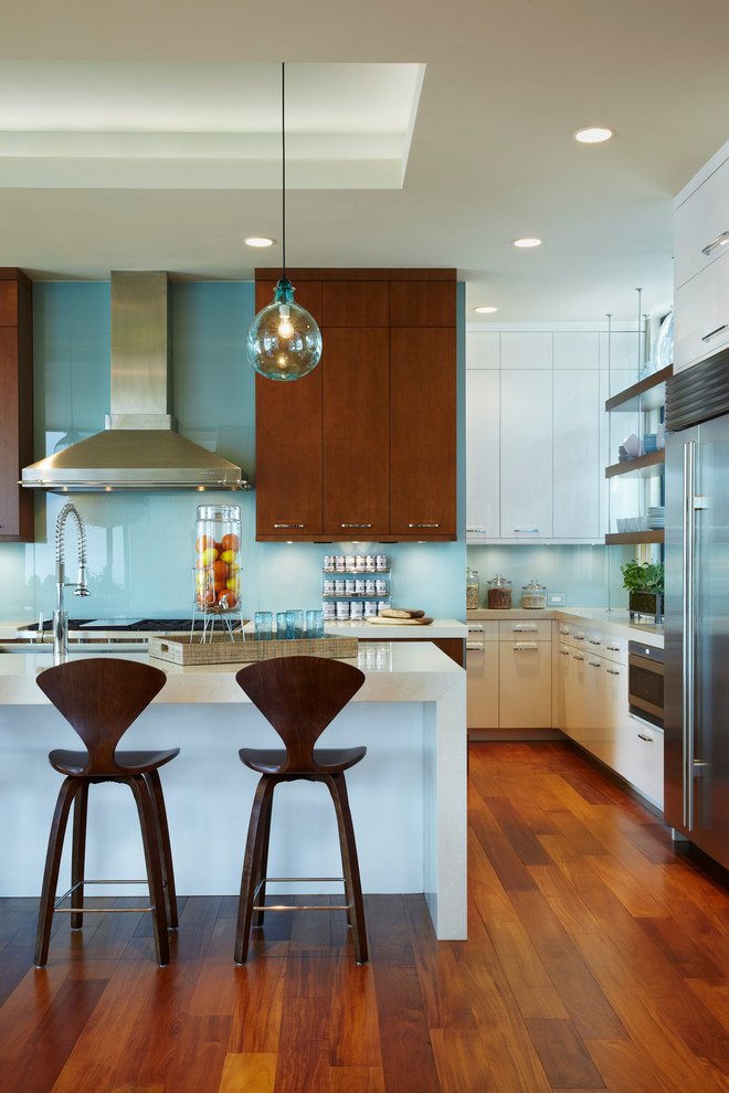 Kitchen - contemporary l-shaped medium tone wood floor kitchen idea in Miami with flat-panel cabinets, dark wood cabinets, blue backsplash, glass sheet backsplash, stainless steel appliances and an island