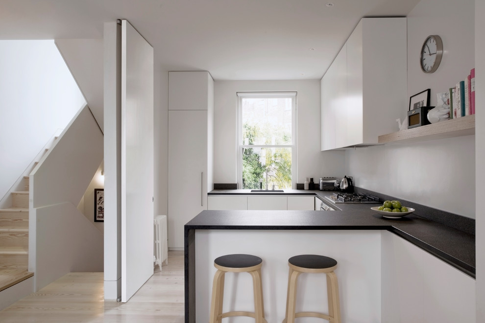 ロンドンにあるコンテンポラリースタイルのおしゃれなキッチン (シングルシンク、フラットパネル扉のキャビネット、白いキャビネット、淡色無垢フローリング、ベージュの床) の写真