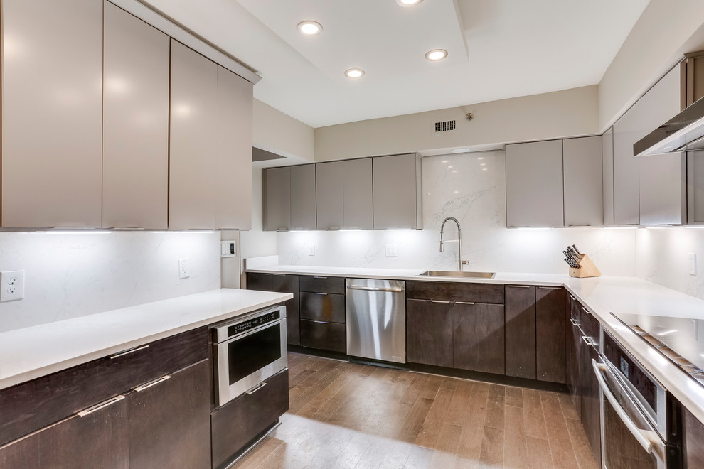 This is an example of a medium sized contemporary enclosed kitchen in DC Metro with a submerged sink, engineered stone countertops, stainless steel appliances, medium hardwood flooring and a breakfast bar.