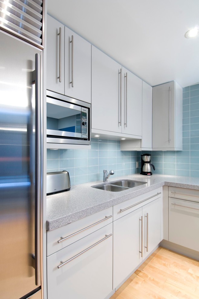 Immagine di una cucina design con lavello a doppia vasca, ante lisce, ante bianche, paraspruzzi blu, paraspruzzi con piastrelle diamantate, elettrodomestici in acciaio inossidabile e parquet chiaro
