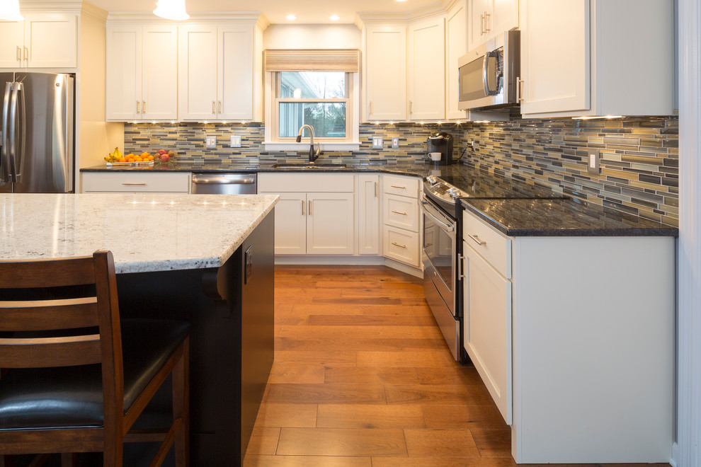 Bild på ett mellanstort funkis kök, med en undermonterad diskho, skåp i shakerstil, vita skåp, granitbänkskiva, flerfärgad stänkskydd, stänkskydd i keramik, rostfria vitvaror, mellanmörkt trägolv och en köksö