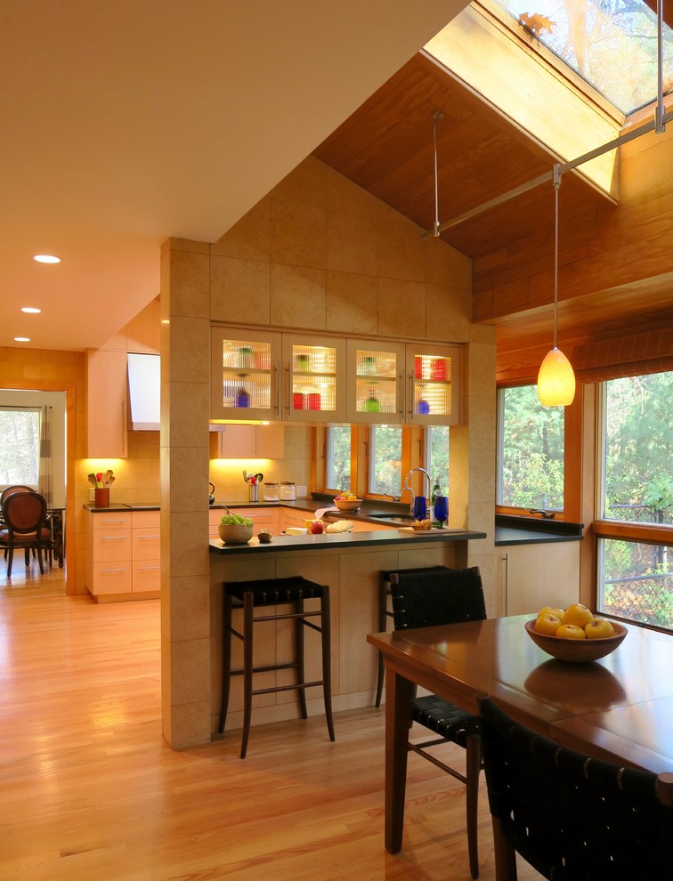Inspiration for a mid-sized contemporary u-shaped medium tone wood floor eat-in kitchen remodel in Boston with an undermount sink, flat-panel cabinets, light wood cabinets, granite countertops, yellow backsplash, stone tile backsplash, stainless steel appliances and a peninsula