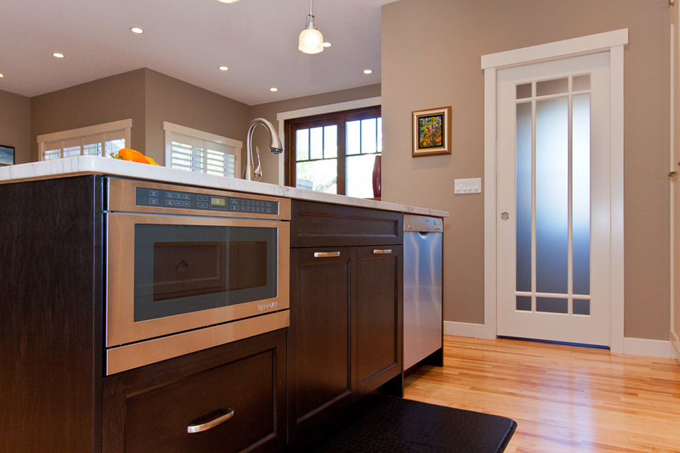 Immagine di una cucina minimal di medie dimensioni con ante in stile shaker, ante in legno bruno, top in quarzite, paraspruzzi bianco, elettrodomestici in acciaio inossidabile e parquet chiaro