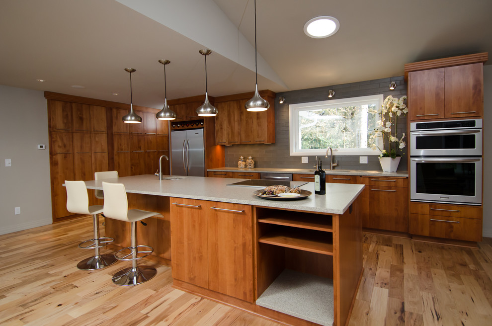 Imagen de cocina contemporánea con armarios con paneles lisos, puertas de armario de madera oscura, salpicadero verde y electrodomésticos de acero inoxidable