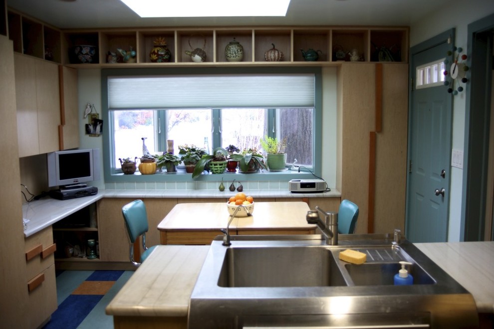 Bild på ett avskilt, mellanstort funkis u-kök, med en rustik diskho, släta luckor, skåp i ljust trä, granitbänkskiva, grönt stänkskydd, stänkskydd i glaskakel, rostfria vitvaror, linoleumgolv och en halv köksö