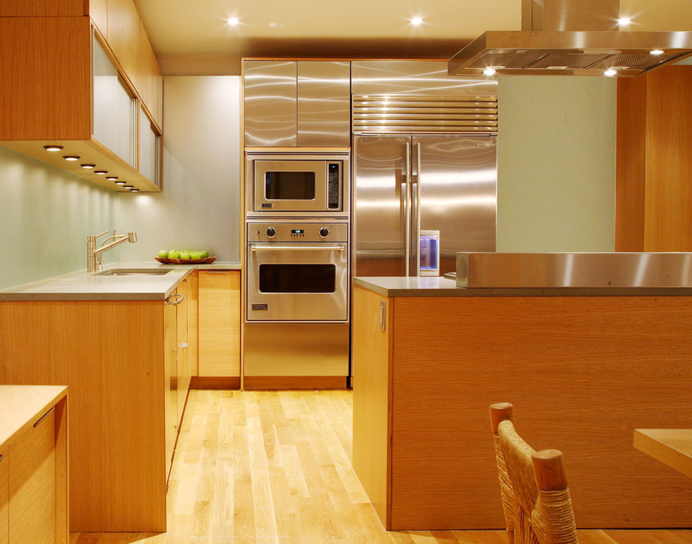 Diseño de cocinas en L actual con fregadero bajoencimera, armarios con paneles lisos, puertas de armario de madera clara y electrodomésticos de acero inoxidable