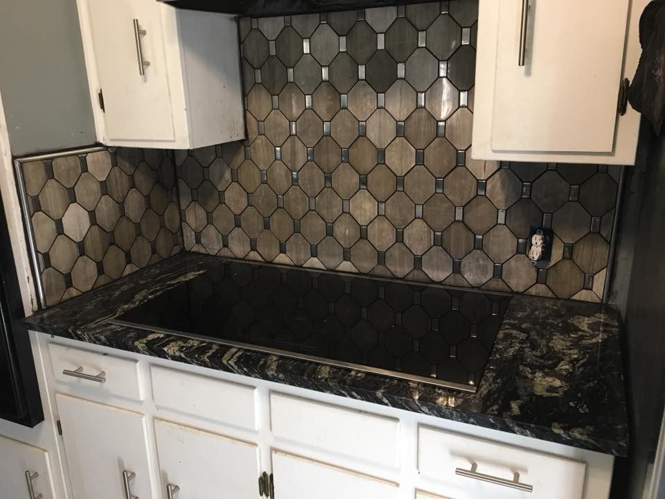Bild på ett mellanstort funkis kök, med släta luckor, vita skåp, granitbänkskiva, brunt stänkskydd, stänkskydd i mosaik och svarta vitvaror