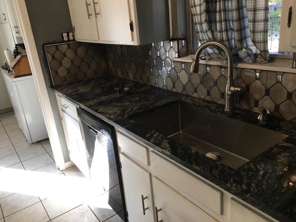 Example of a mid-sized trendy galley ceramic tile and beige floor open concept kitchen design in Austin with a drop-in sink, flat-panel cabinets, white cabinets, granite countertops, brown backsplash, mosaic tile backsplash, black appliances and no island