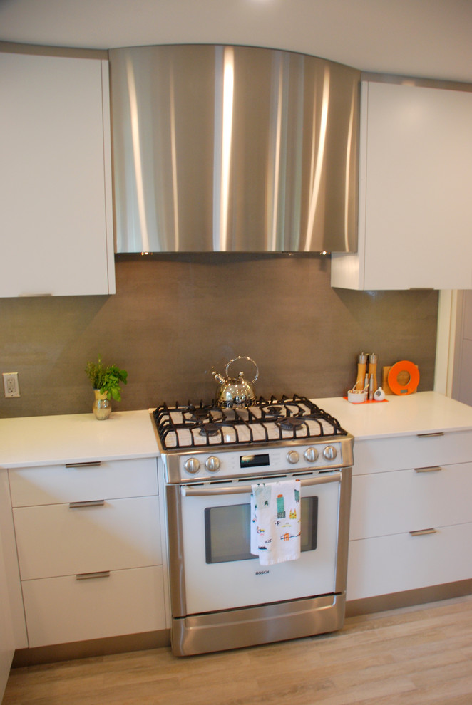 Photo of a medium sized scandi u-shaped kitchen in Calgary with a submerged sink, flat-panel cabinets, white cabinets, grey splashback, stainless steel appliances, light hardwood flooring and an island.