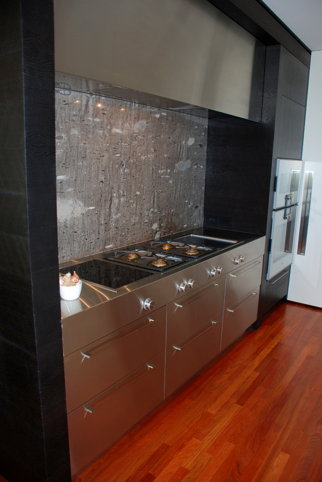 Exempel på ett stort modernt u-kök, med en undermonterad diskho, släta luckor, bänkskiva i kvartsit, rostfria vitvaror, mellanmörkt trägolv, en köksö, grått stänkskydd, stänkskydd i sten och skåp i rostfritt stål