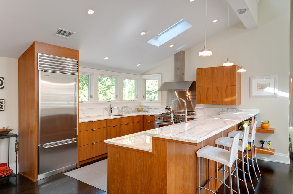 Moderne Küche in U-Form mit Küchengeräten aus Edelstahl, flächenbündigen Schrankfronten, hellbraunen Holzschränken, Küchenrückwand in Weiß und Rückwand aus Stein in New York