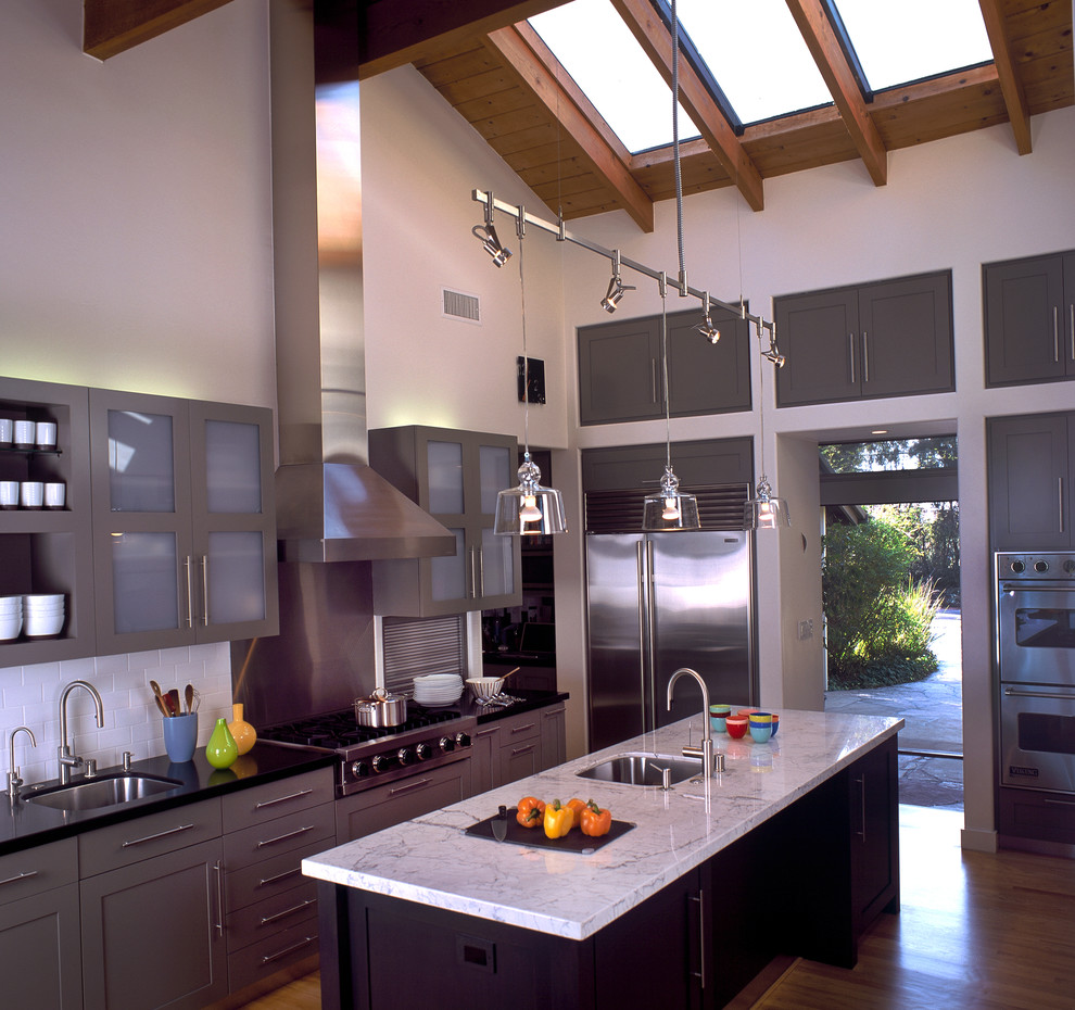 Foto de cocina contemporánea con salpicadero de azulejos tipo metro, electrodomésticos de acero inoxidable, armarios estilo shaker, puertas de armario grises y salpicadero blanco