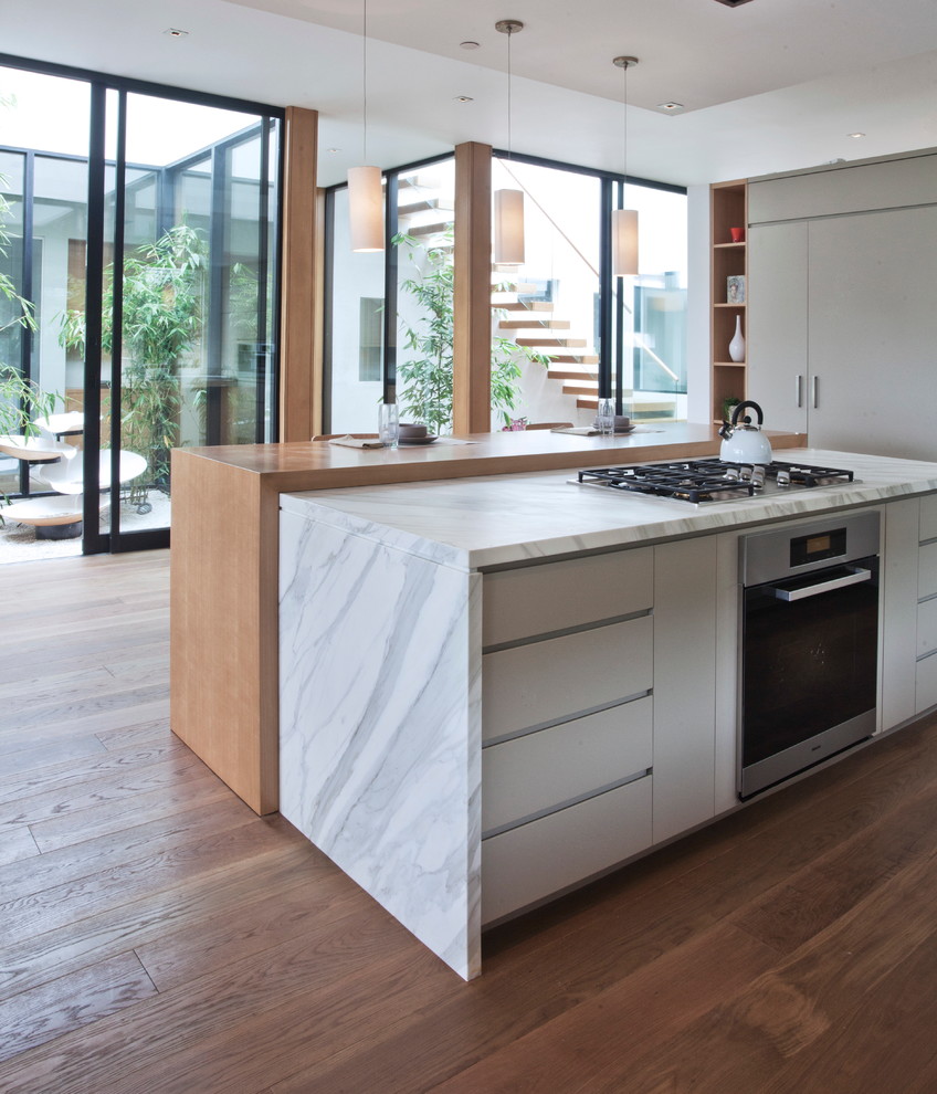 Cette image montre une cuisine design avec un placard à porte plane et des portes de placard blanches.
