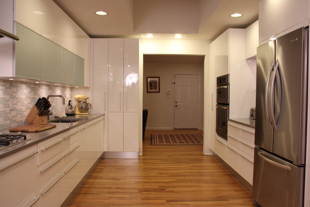 Zweizeilige Moderne Küche mit Unterbauwaschbecken, flächenbündigen Schrankfronten, weißen Schränken, bunter Rückwand, Rückwand aus Mosaikfliesen und Küchengeräten aus Edelstahl in New York