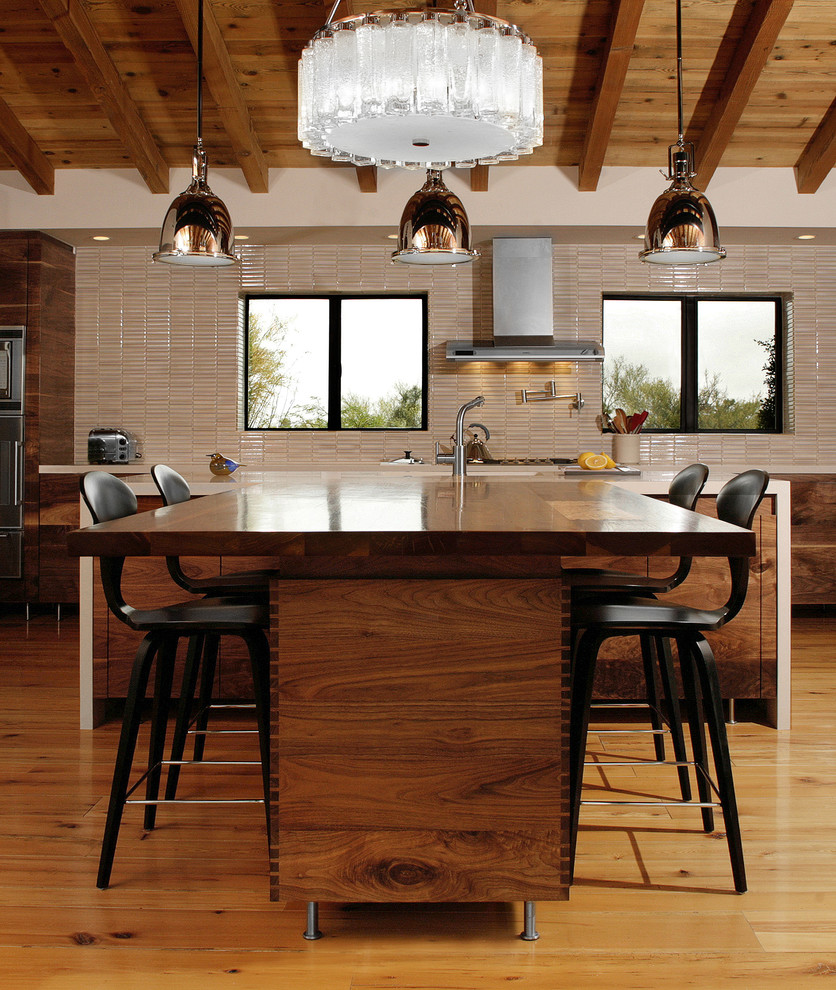 Moderne Wohnküche mit braunem Holzboden, Kücheninsel, flächenbündigen Schrankfronten, dunklen Holzschränken und Küchenrückwand in Beige in Los Angeles