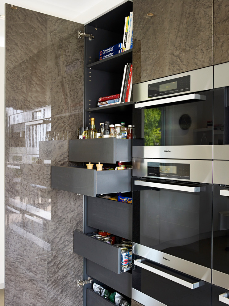 Contemporary kitchen in London with flat-panel cabinets, black cabinets and stainless steel appliances.