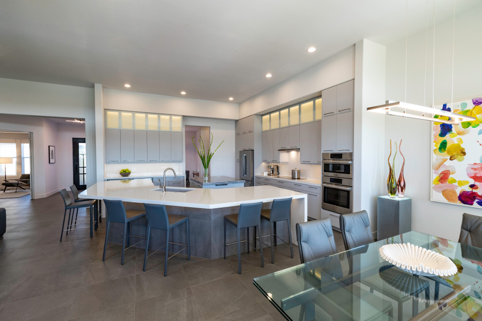Large contemporary open plan kitchen in Phoenix with a submerged sink, flat-panel cabinets, grey cabinets, engineered stone countertops, white splashback, engineered quartz splashback, stainless steel appliances, porcelain flooring, multiple islands, grey floors and white worktops.