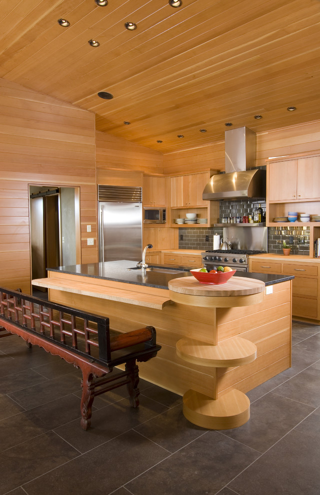Moderne Küche mit flächenbündigen Schrankfronten, hellbraunen Holzschränken und Rückwand aus Metrofliesen in Sonstige