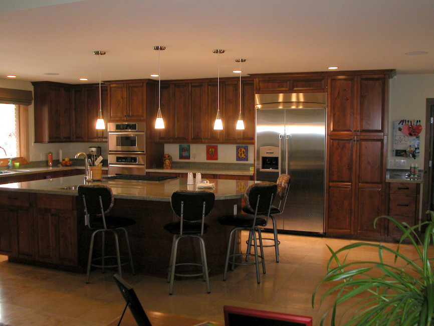 Foto på ett stort vintage l-kök, med en undermonterad diskho, luckor med upphöjd panel, skåp i mörkt trä, rostfria vitvaror och en köksö