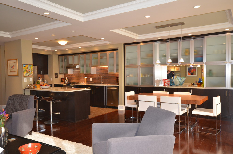 Пример оригинального дизайна: кухня-гостиная в современном стиле с стеклянными фасадами, фасадами из нержавеющей стали, коричневым фартуком и барной стойкой