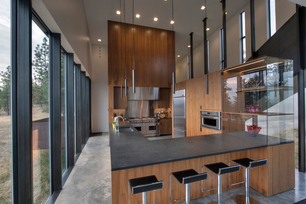 Exempel på ett modernt kök, med en dubbel diskho, släta luckor, skåp i mellenmörkt trä, stänkskydd med metallisk yta, rostfria vitvaror och betonggolv