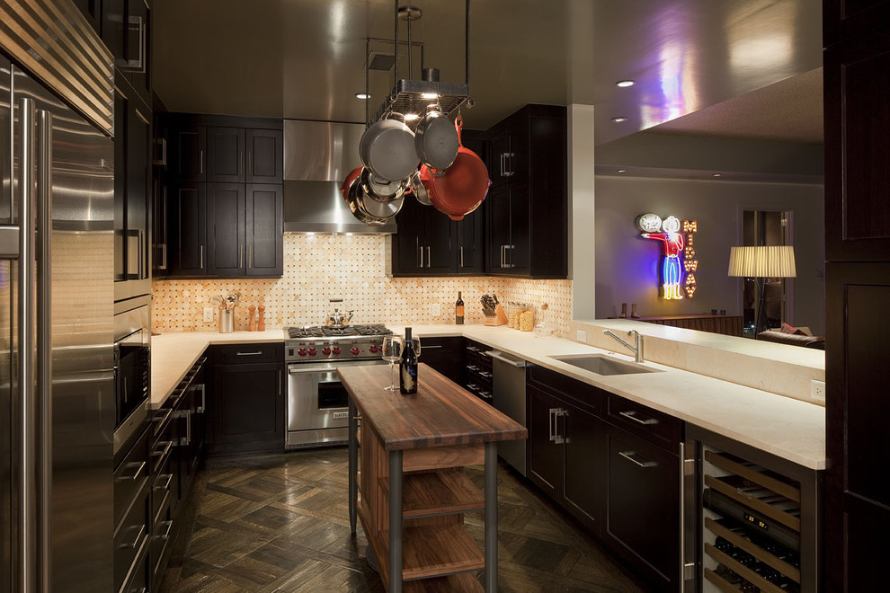 На фото: п-образная кухня в современном стиле с техникой из нержавеющей стали, врезной мойкой, темными деревянными фасадами и разноцветным фартуком с