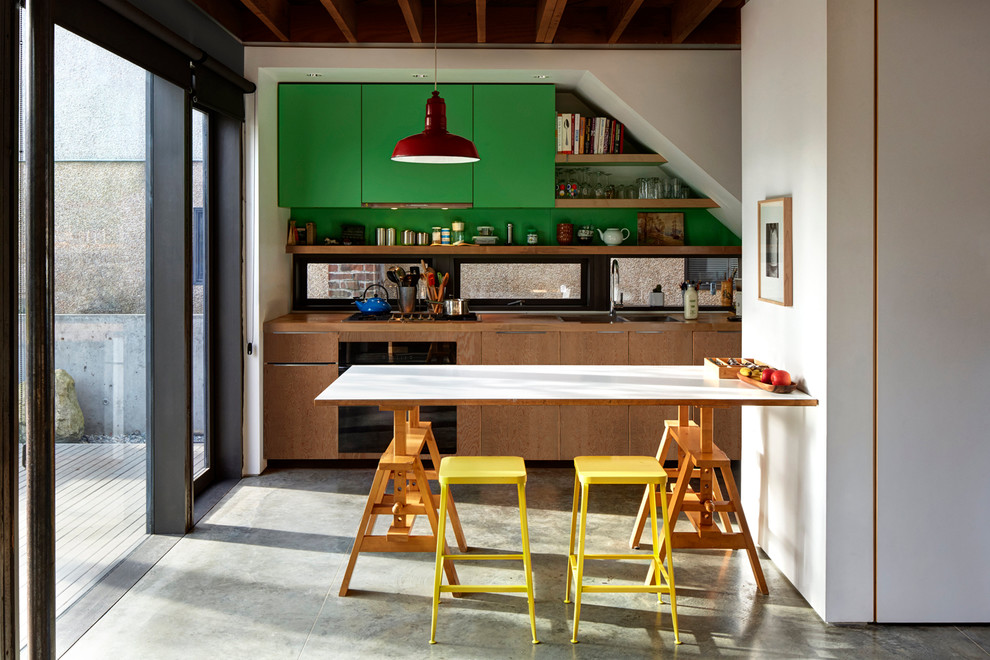 Modern inredning av ett kök och matrum, med en dubbel diskho, släta luckor, gröna skåp, träbänkskiva och betonggolv